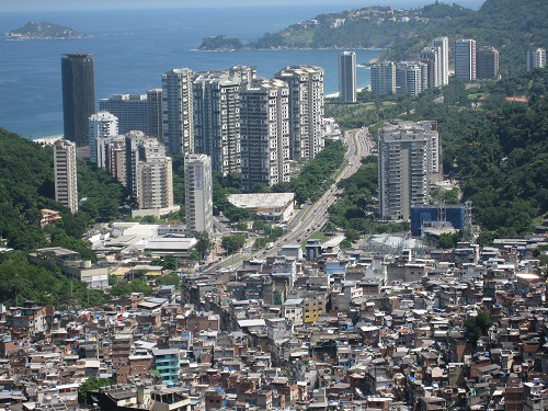 In Rio de Janeiro, high-rise buildings loom in front of Rocinha, one of the largest favelas in Brazil. Wikimedia Commons